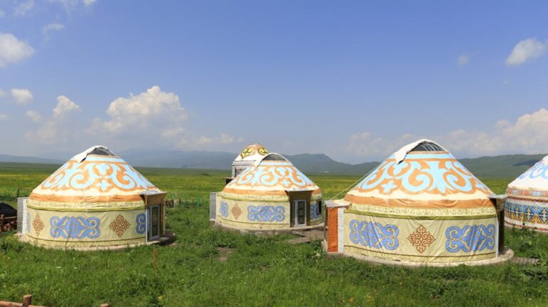 Colorful yurts on a green field under blue skies, showcasing traditional nomadic living.
